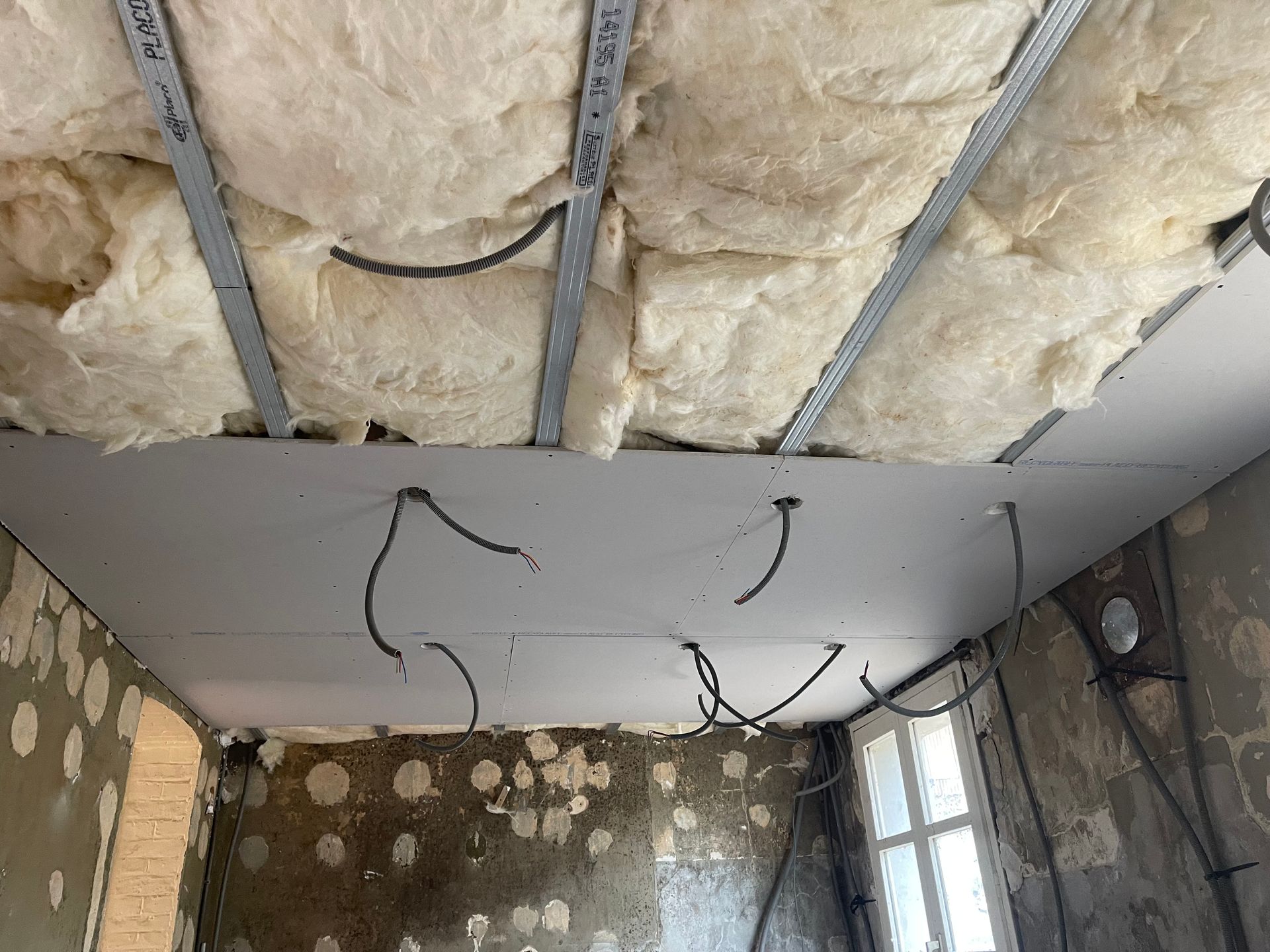 Isolant sous plancher installé et câbles passés avant pose des plaques de plâtre