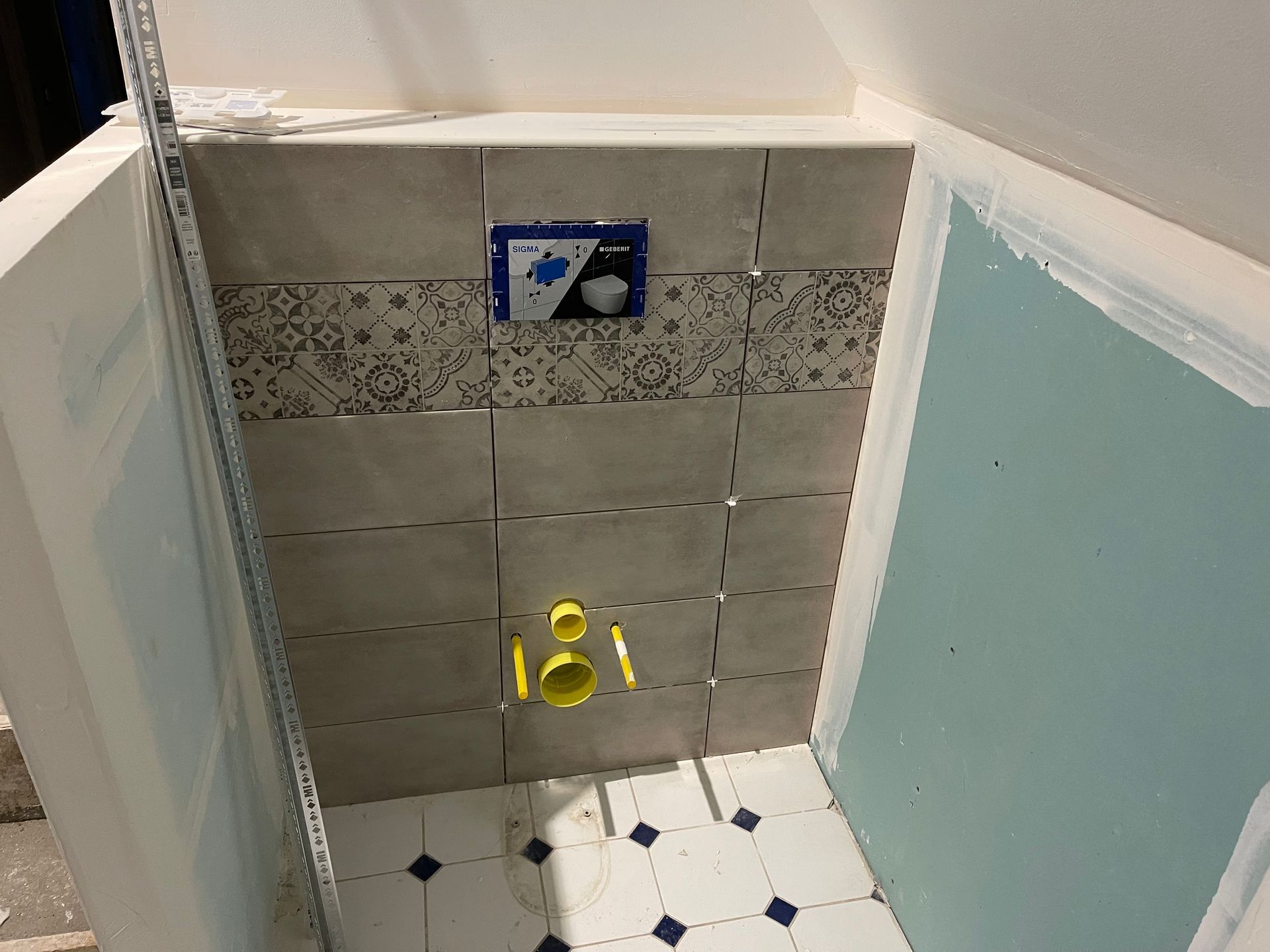 Faïence avec frise posée sur le bloc chasse d'eau de futures toilettes suspendues