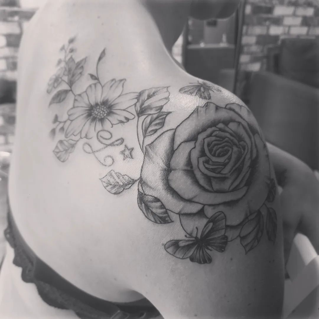 Tatouage floral sur une épaule et en partie sur une omoplate