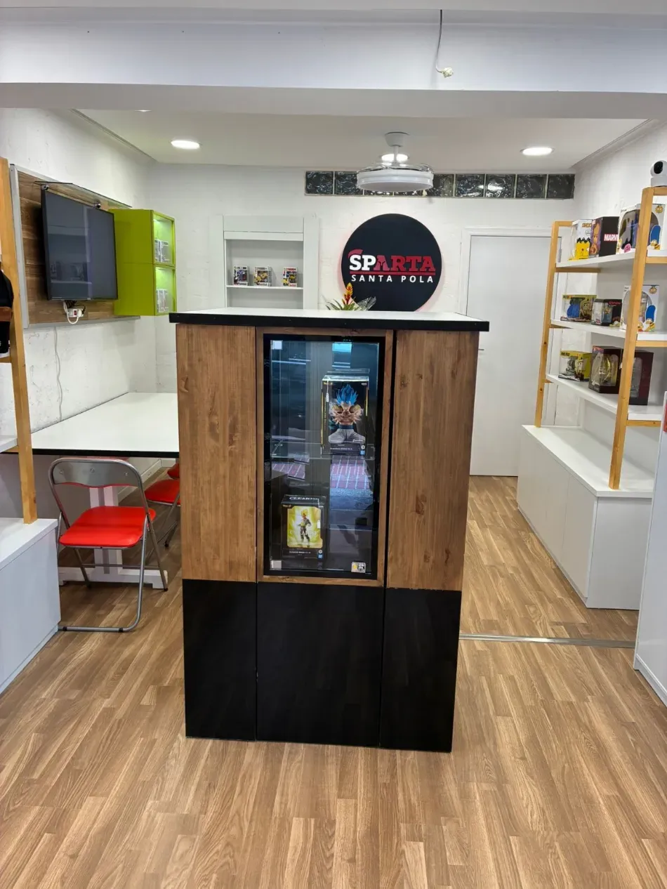 Interior de una pequeña tienda con un quiosco refrigerado de madera para bebidas y estantes a lo largo de las paredes.