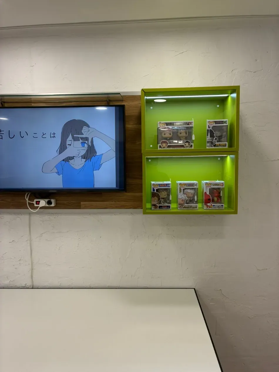 Pantalla montada en la pared y estante verde con pequeños artículos empaquetados en una habitación.