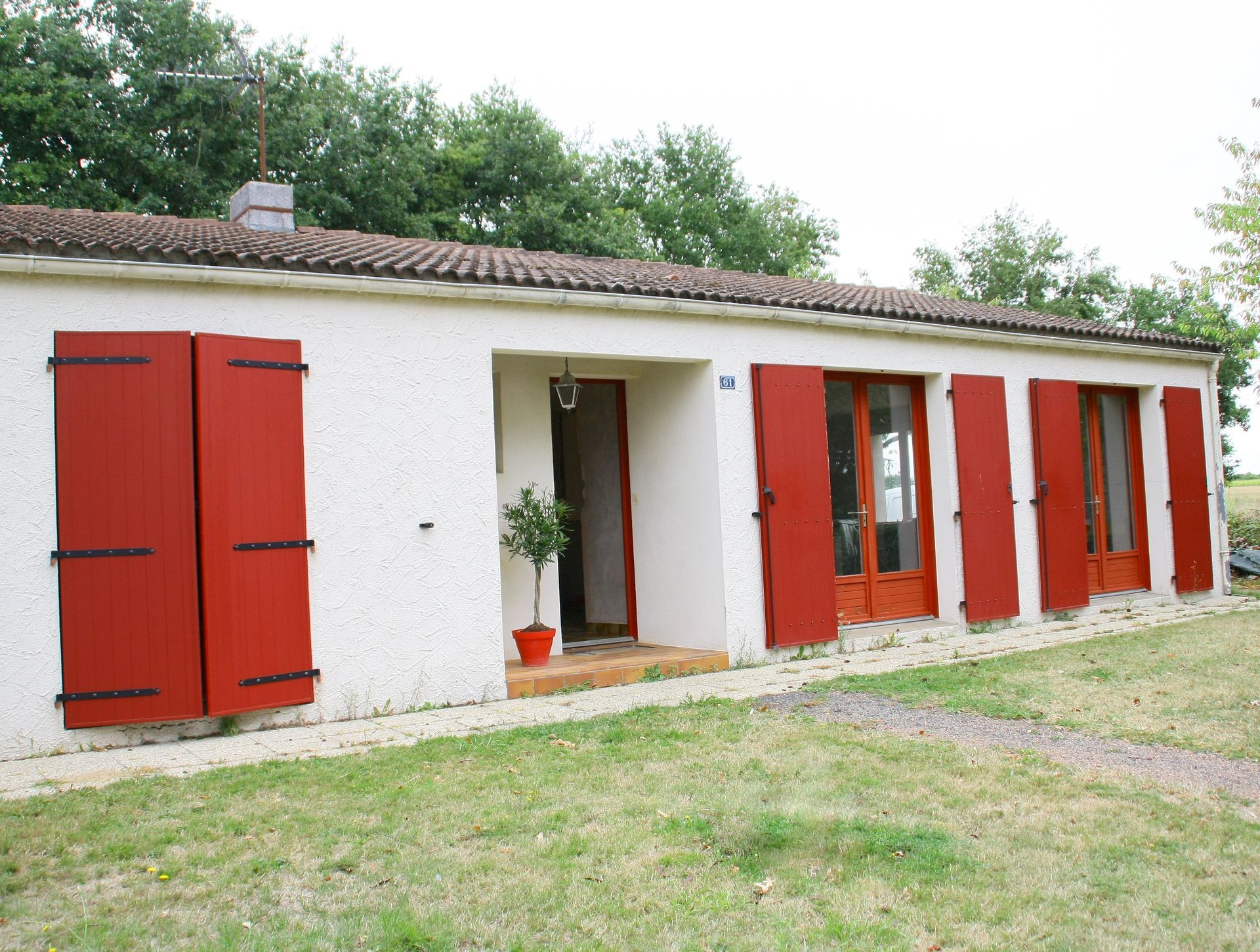 Façade de maison avec des volets en bois rouge