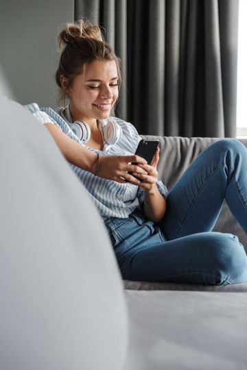 Personne assise sur un canapé avec un téléphone dans les mains