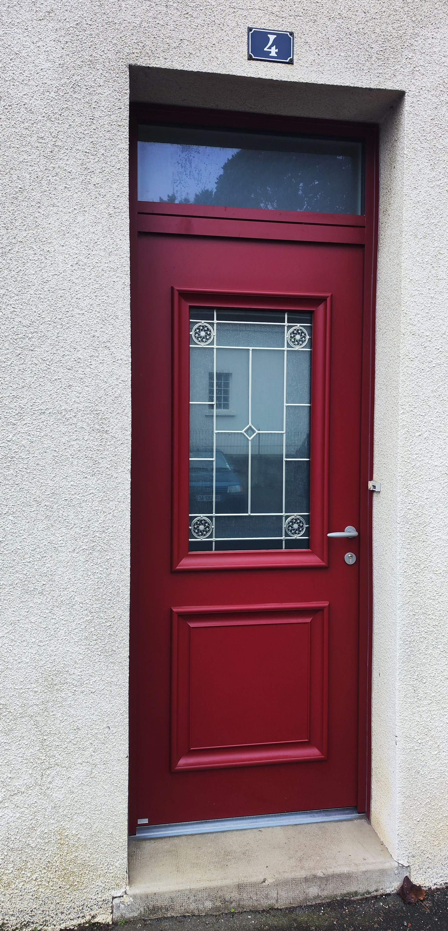 Porte d'entrée rouge avec un vitrage central décoratif