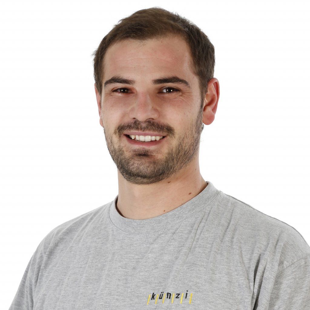 Ein Mann mit Bart und einem grauen T-Shirt mit der Aufschrift „psnzi“