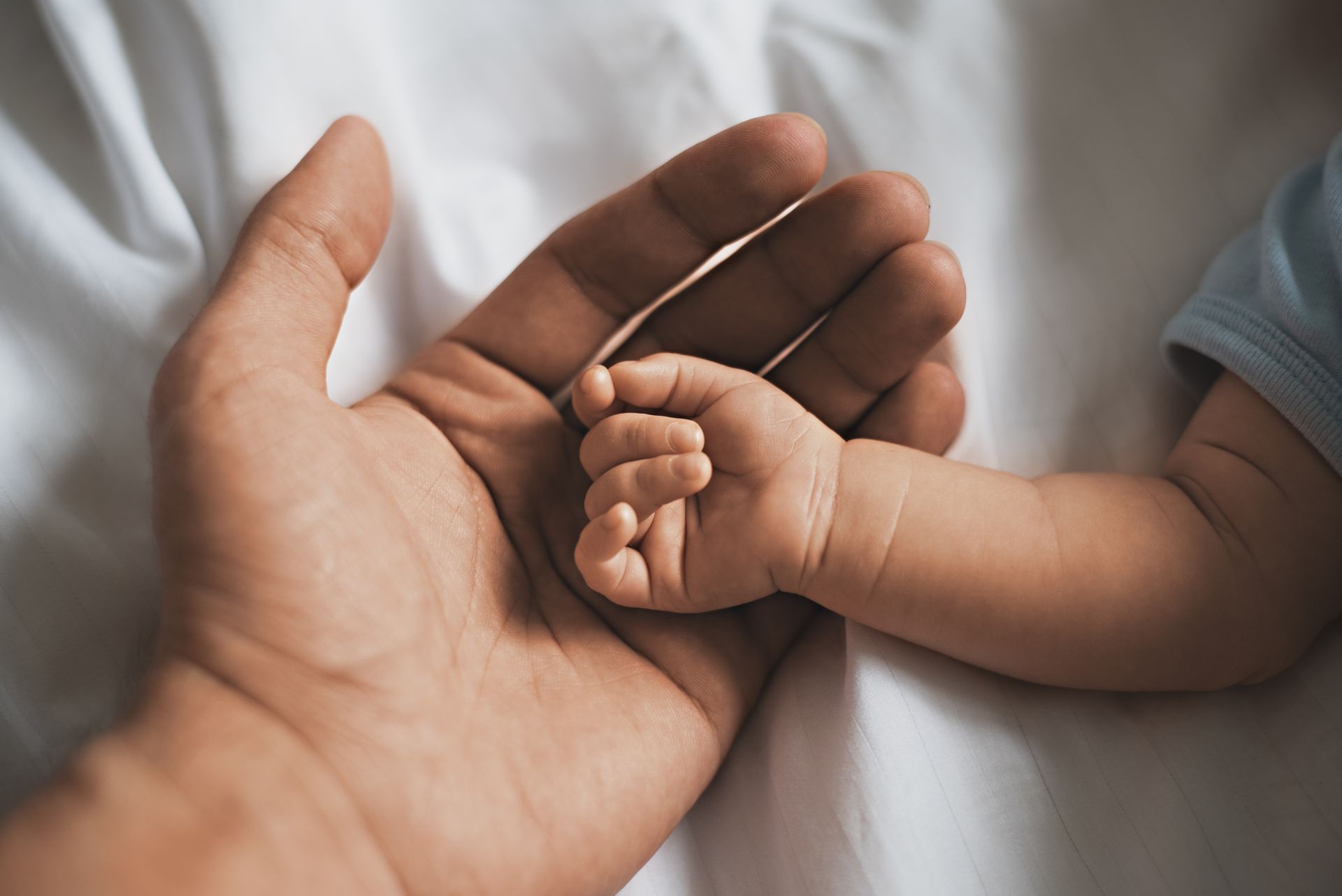 Main d'homme ouverte sur celle d'un bébé