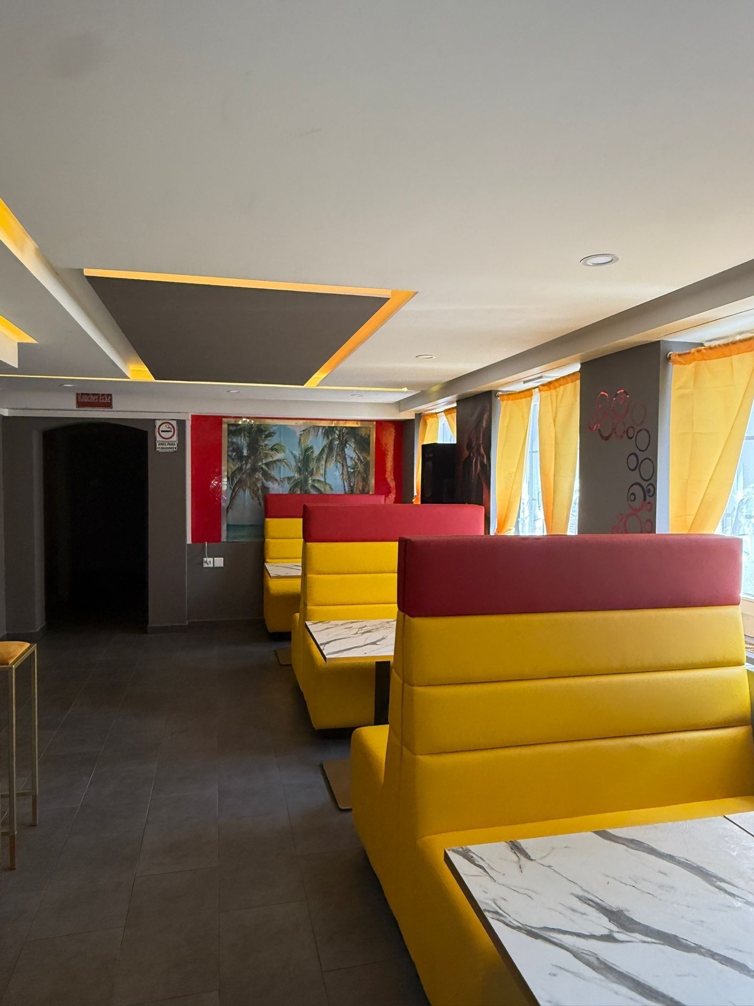 Moderne Lounge mit weissen Sofas, goldener Dekoration, dunklem Fliesenboden und roter Akzentwand mit Neonreklame