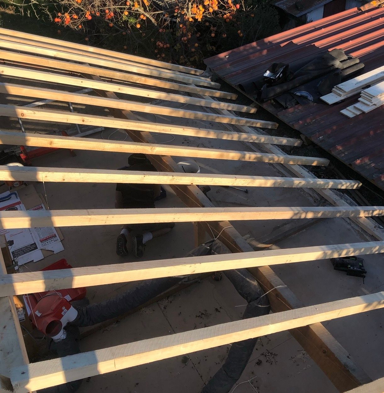 Des chevrons en bois posés sur un toit, avec des outils de construction visibles.