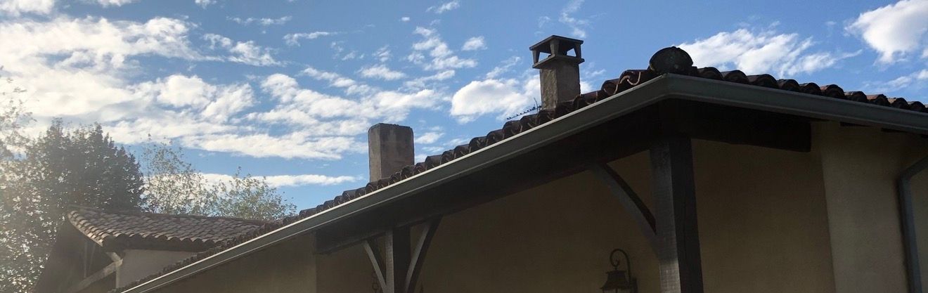 Maison avec une cheminée sur fond de ciel bleu nuageux.
