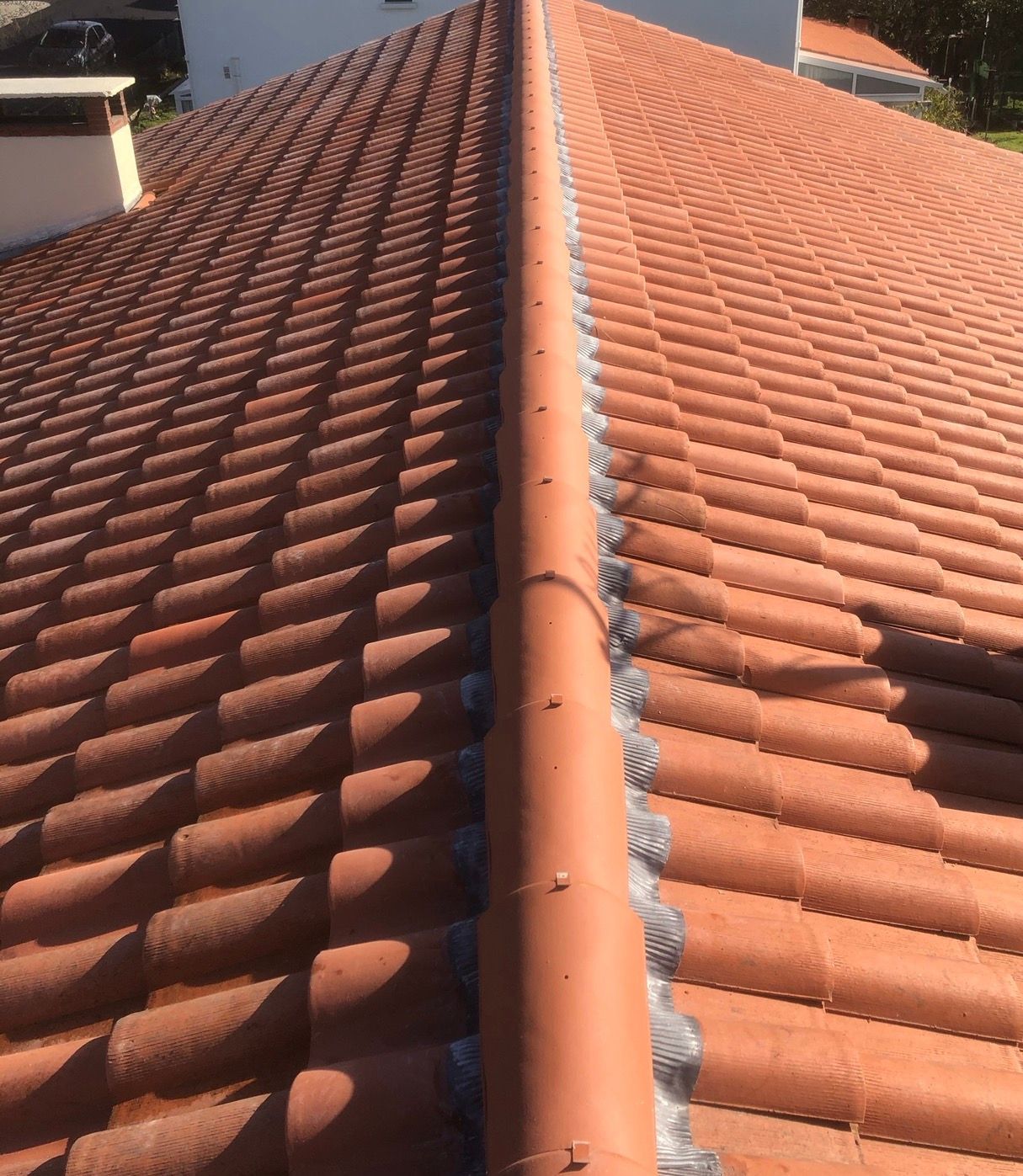 Toit de tuiles rouges avec une arête centrale, vu du dessus.