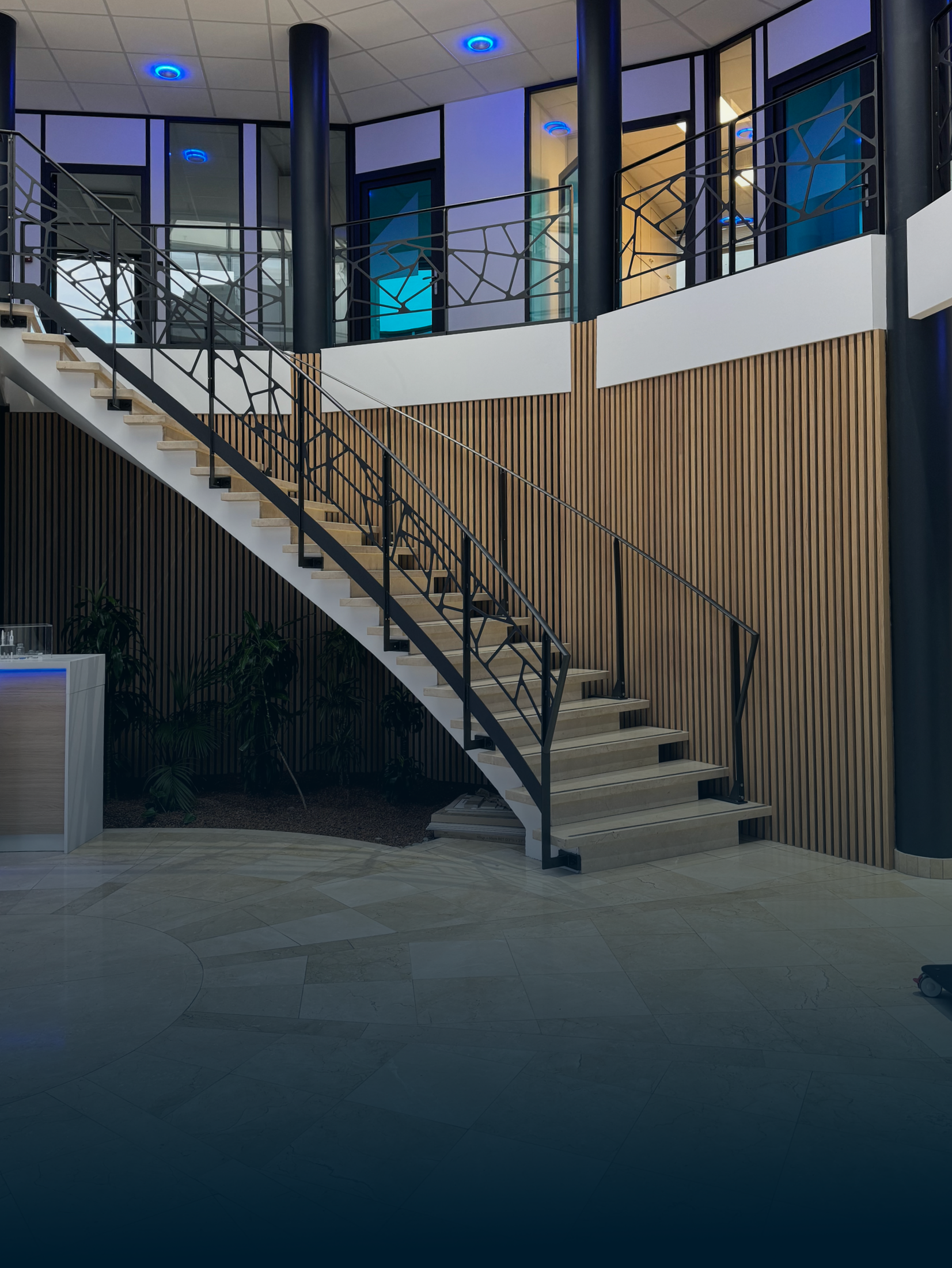 Quatre chaises orange autour d'une petite table devant une fenêtre, une plante et une voiture à l'extérieur.