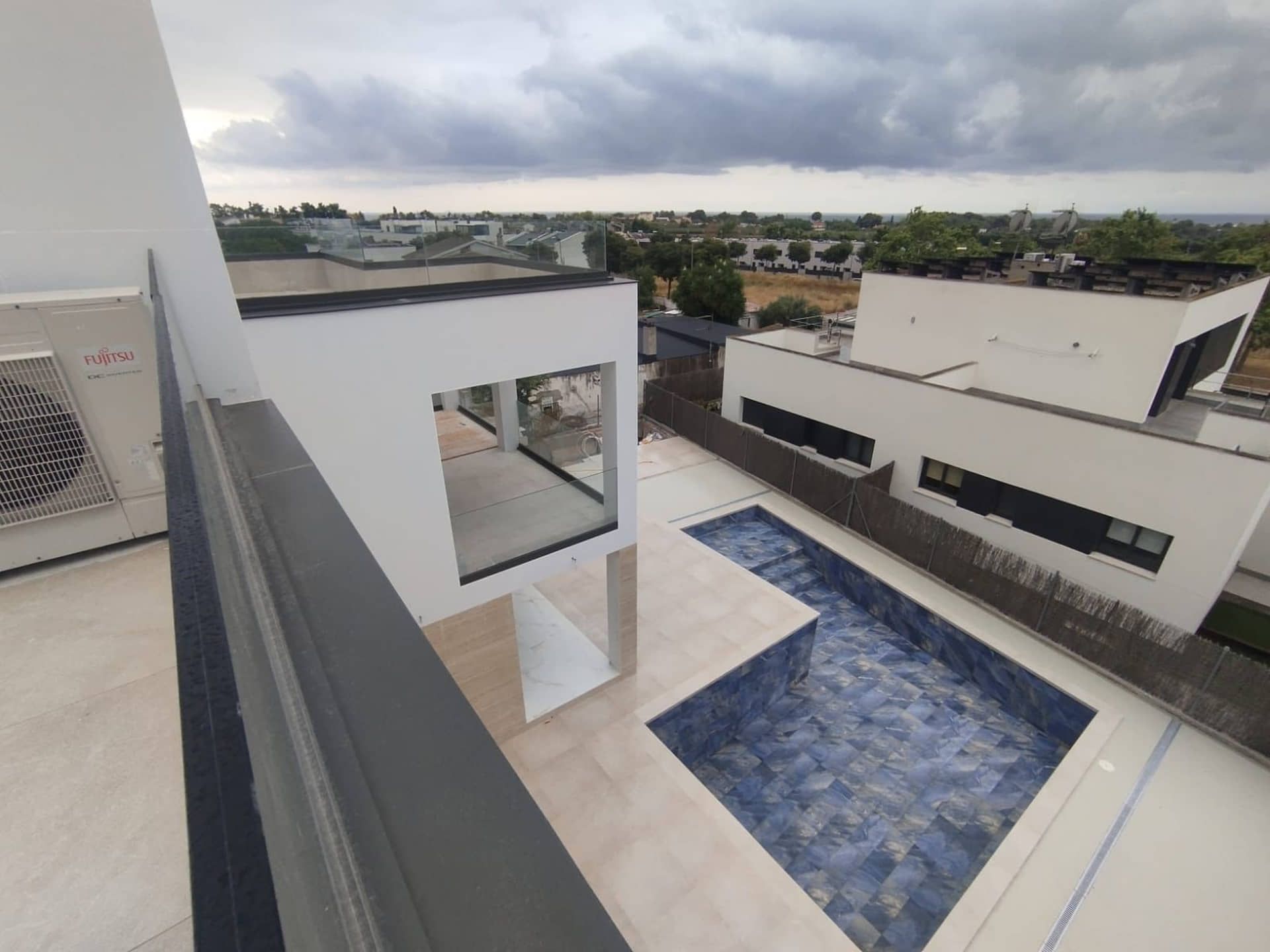 Edificios blancos modernos con piscina, cielo nublado.