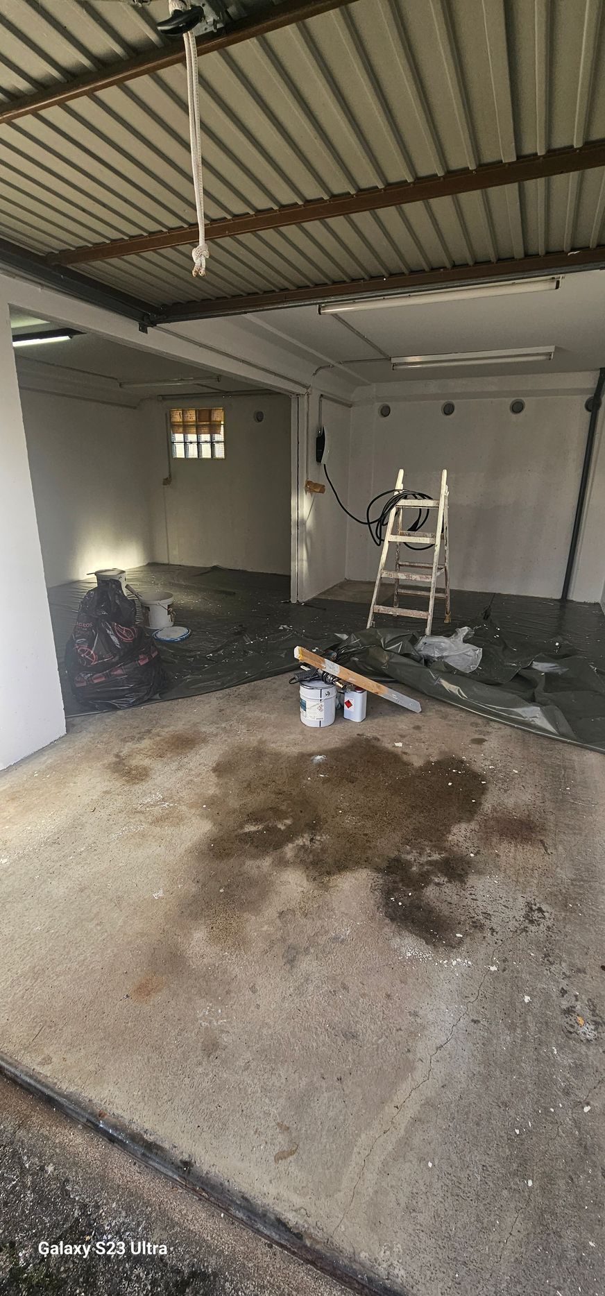 Eine Person streicht an einem Seil die Aussenwand eines hohen Gebäudes.