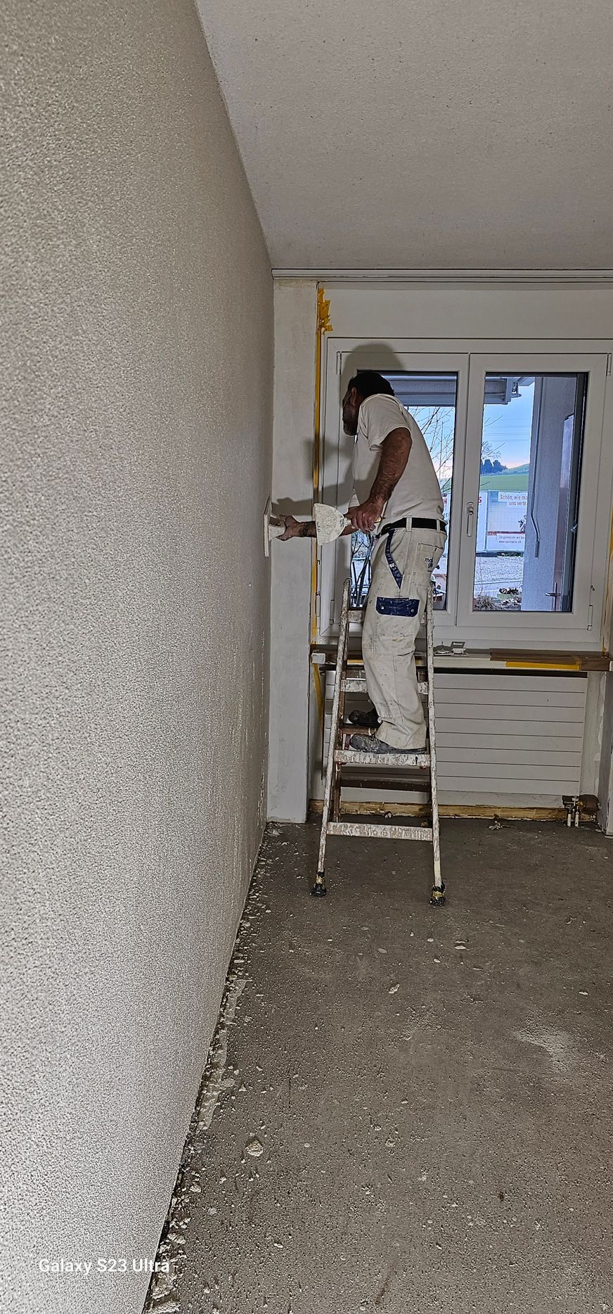 Eine Person streicht an einem Seil die Aussenwand eines hohen Gebäudes.