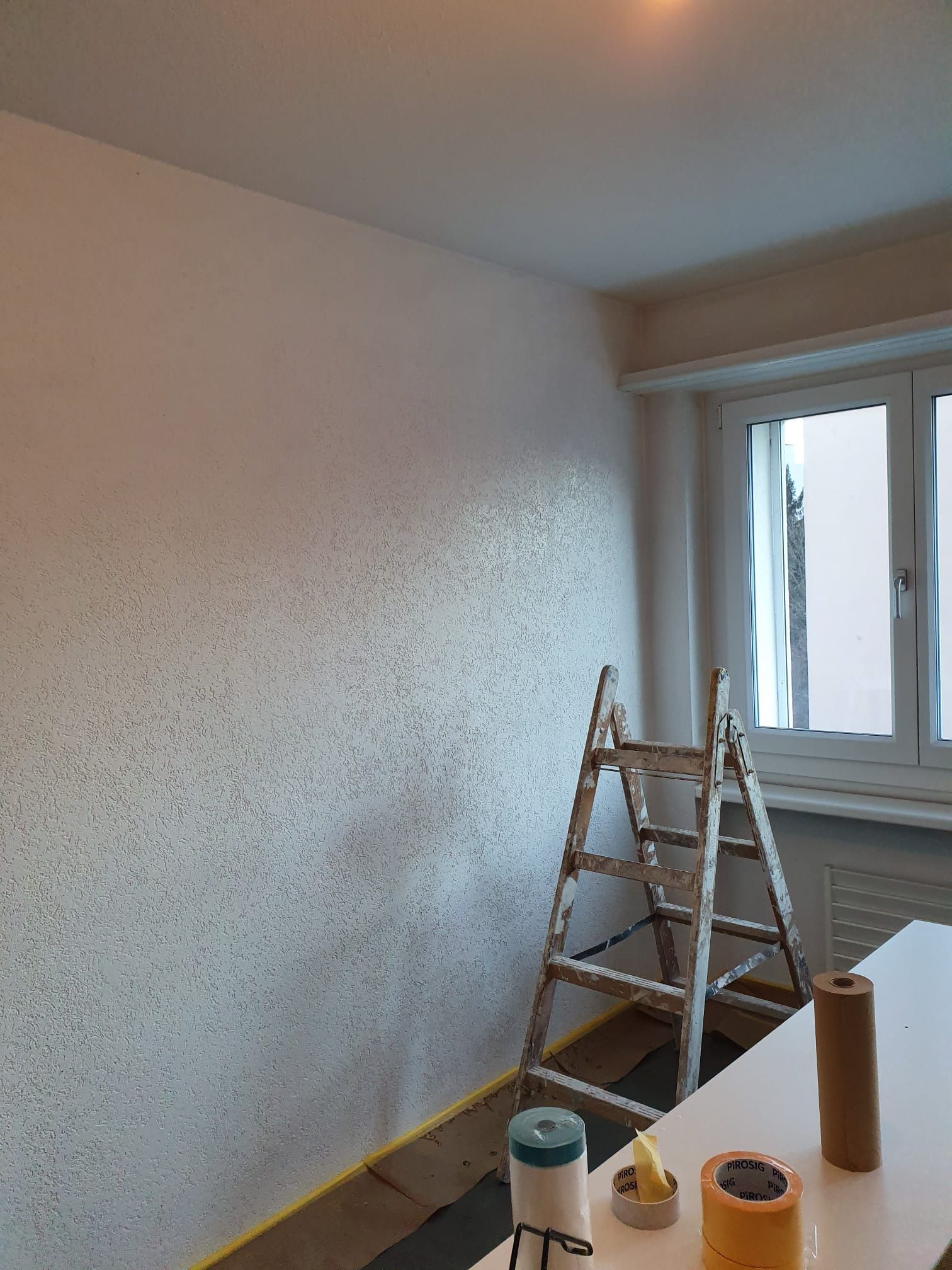 Zimmer wird gestrichen; strukturierte Wand, Leiter, Malutensilien.