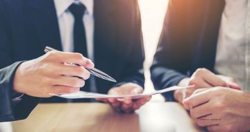 Schöffel & Partner Partnerschaftsgesellschaft Steuerberater - Rechtsanwalt Mann im Anzug geht ein Dokument mit einem Mandanten durch