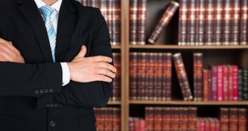 Schöffel & Partner Partnerschaftsgesellschaft Steuerberater - Rechtsanwalt Mann im Anzug steht vor einem Bücherregal