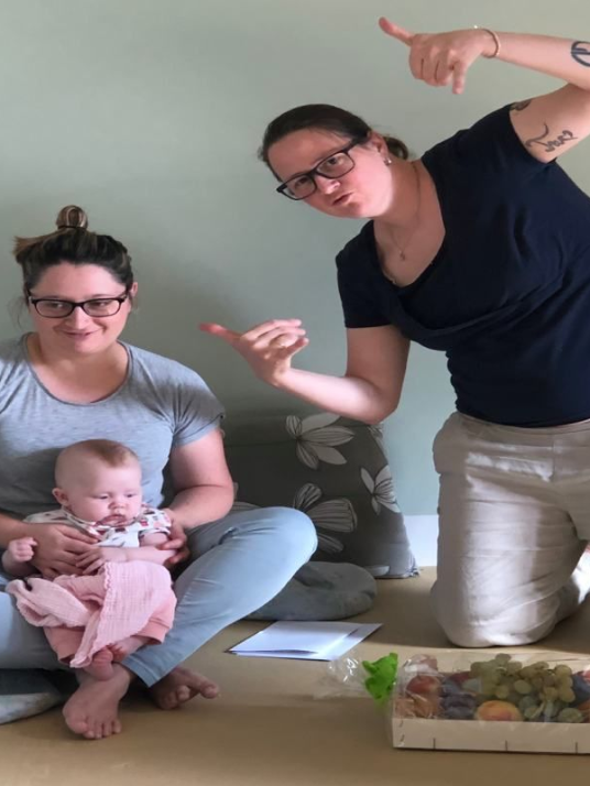 Due donne sorridono con un neonato in braccio