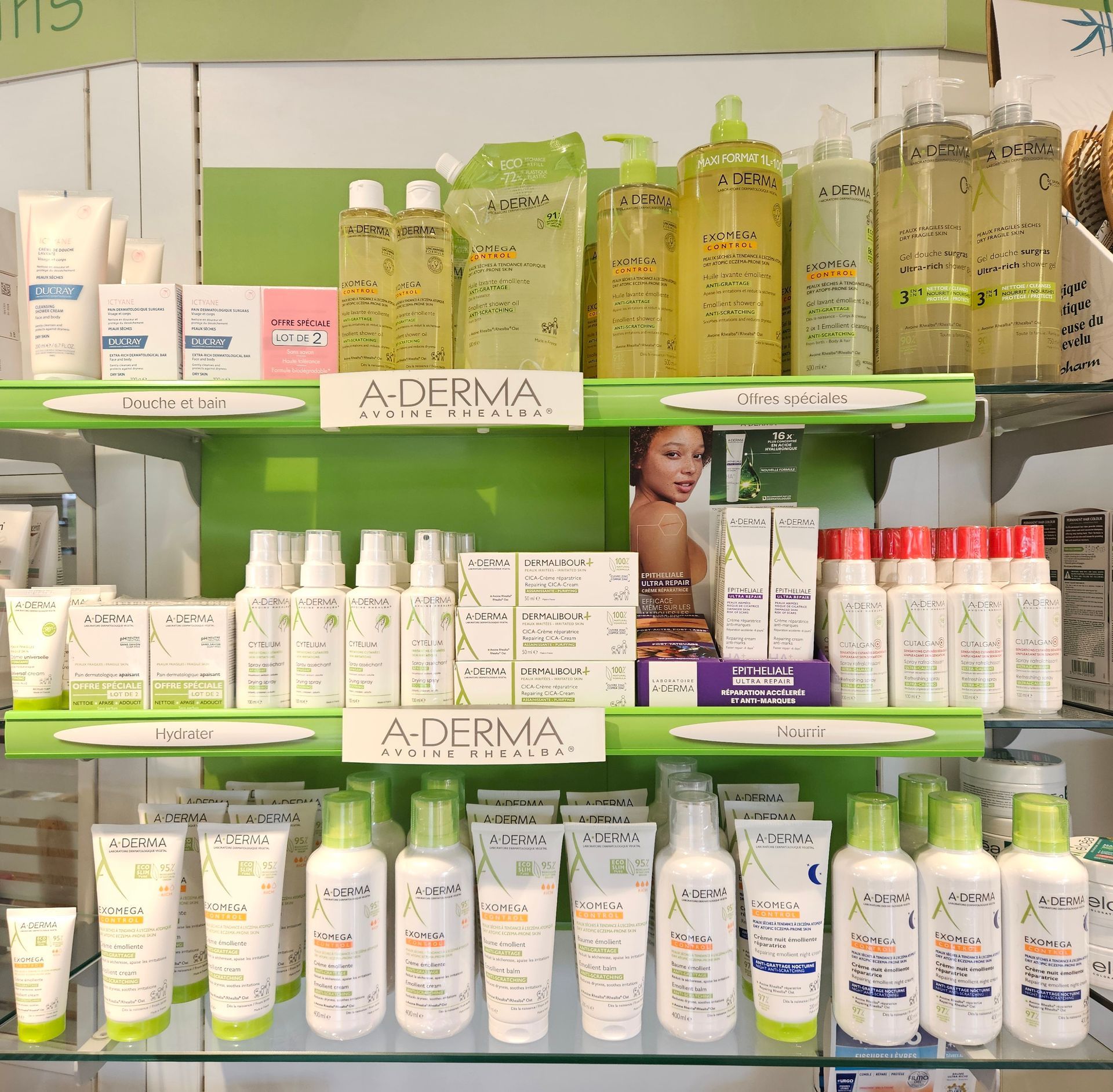 Les produits de soin Aderma sont présentés sur les étagères du magasin, avec un emballage vert et blanc.