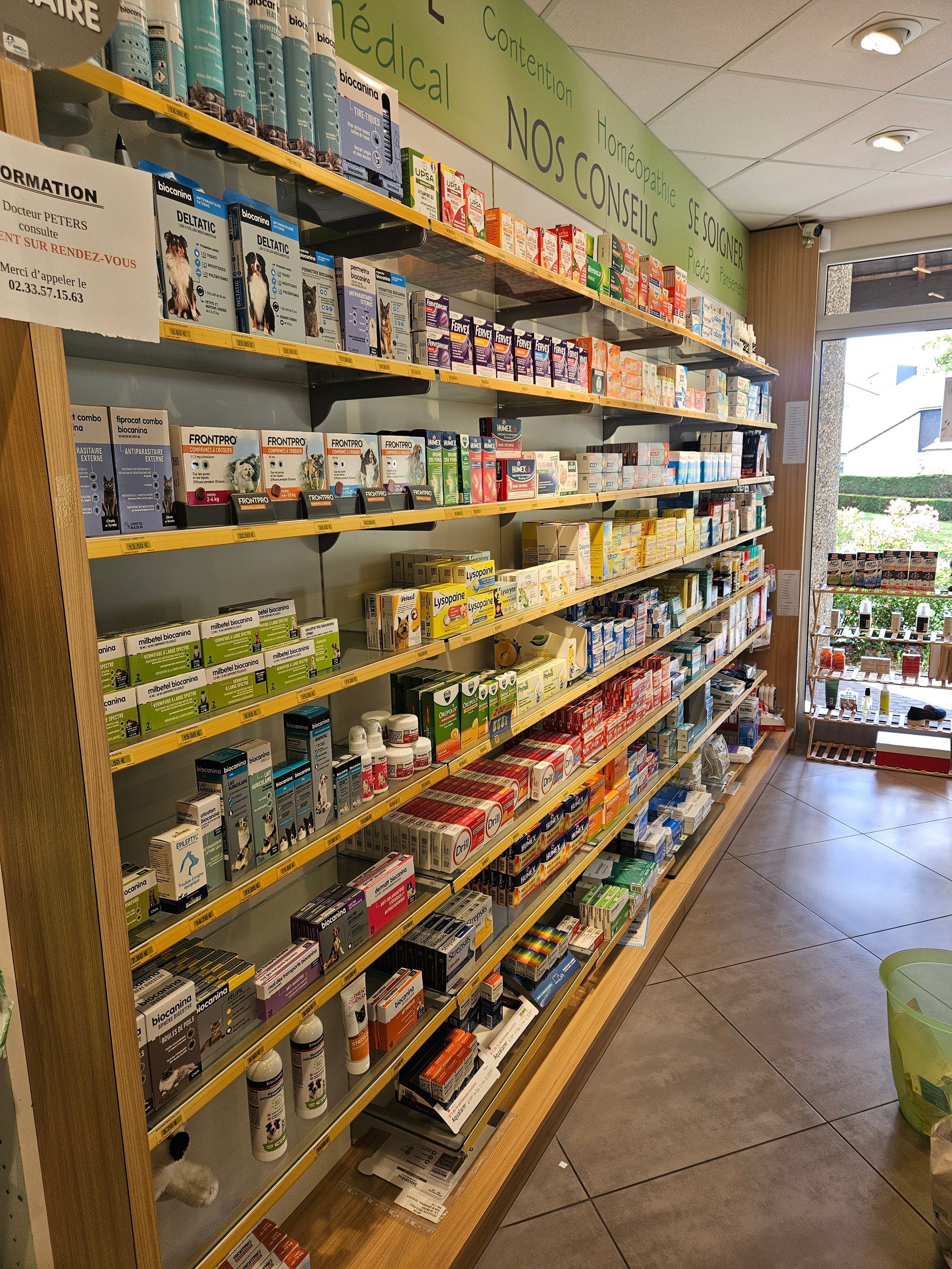 Rayon de produits emballés variés (collations et boissons) dans une allée de supérette, avec une entrée lumineuse en arrière-plan.