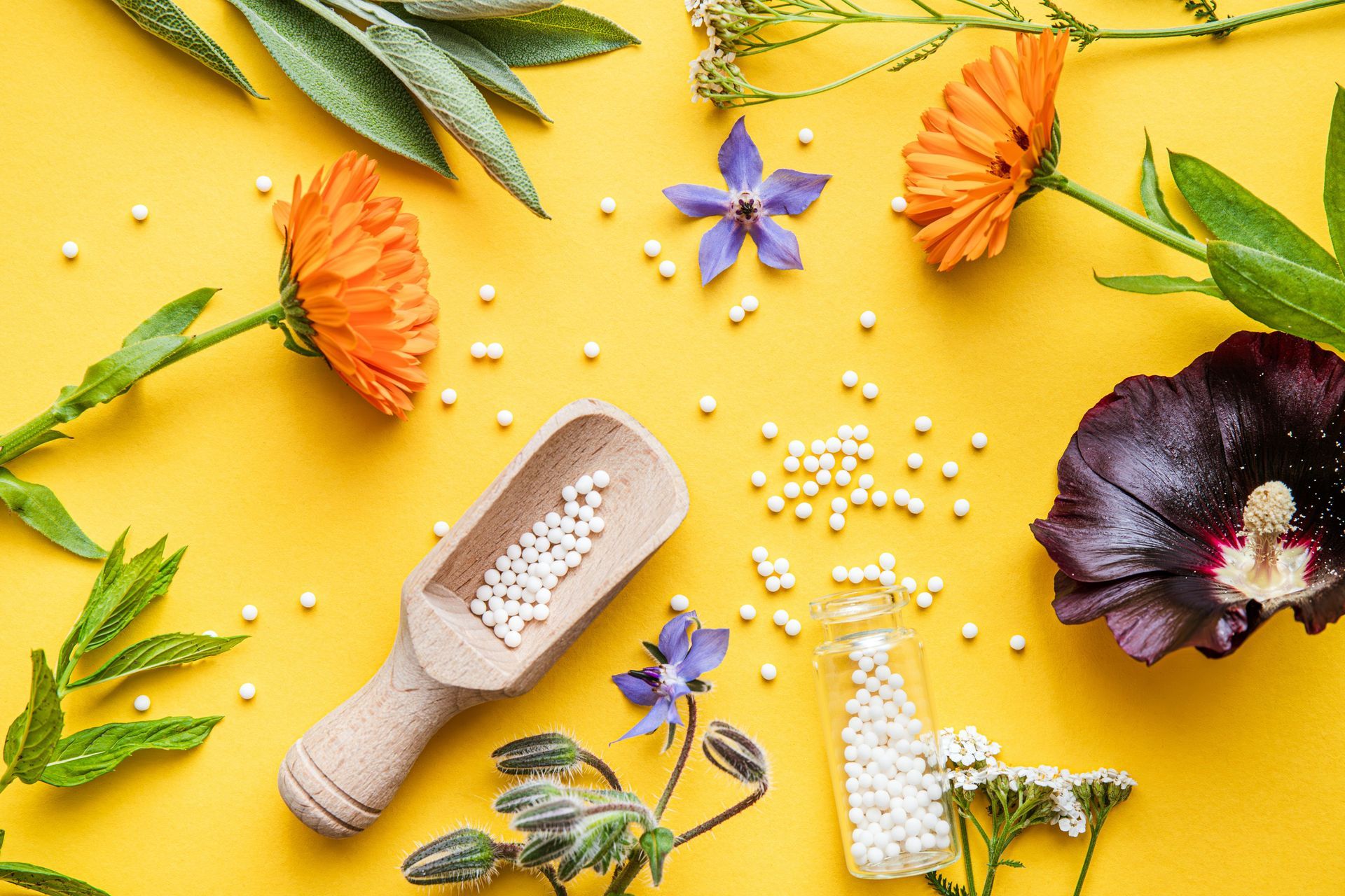 Assortiment d'articles de spa à base de plantes et de fleurs sur un fond jaune vif avec des perles blanches éparses