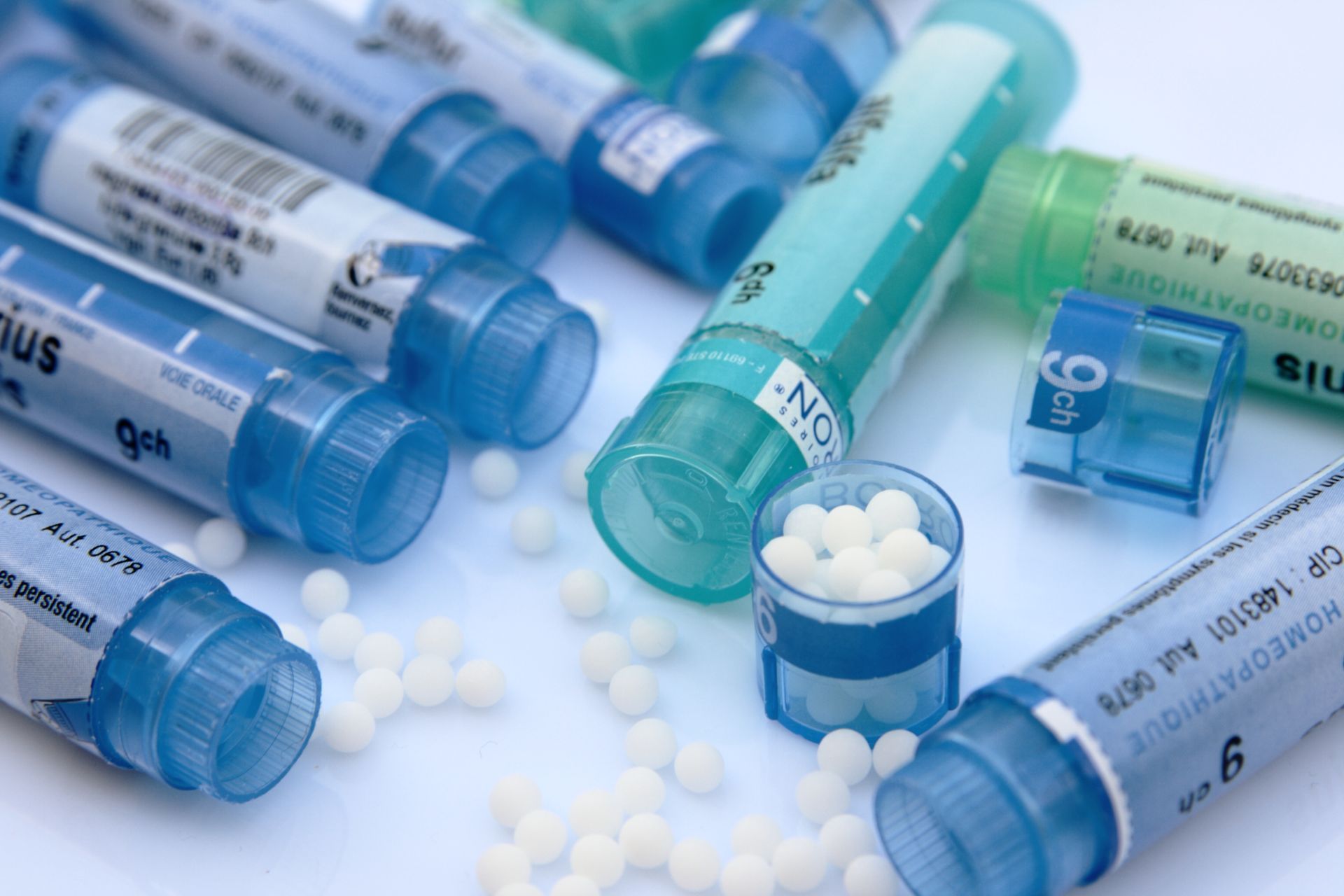 Tubes de pilules bleus et turquoise contenant des comprimés blancs dispersés sur une surface blanche