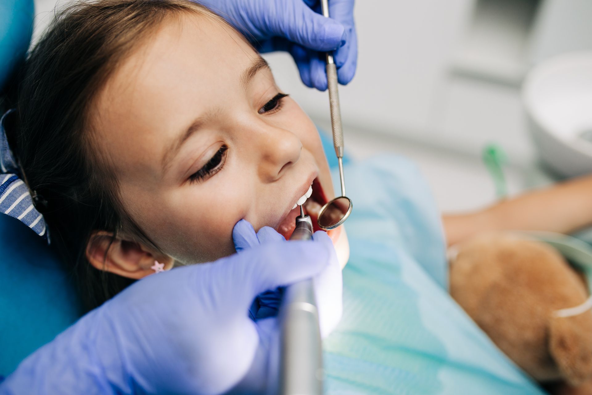 Un dentiste examine la bouche d'un enfant avec des instruments dentaires et des gants dans une clinique.