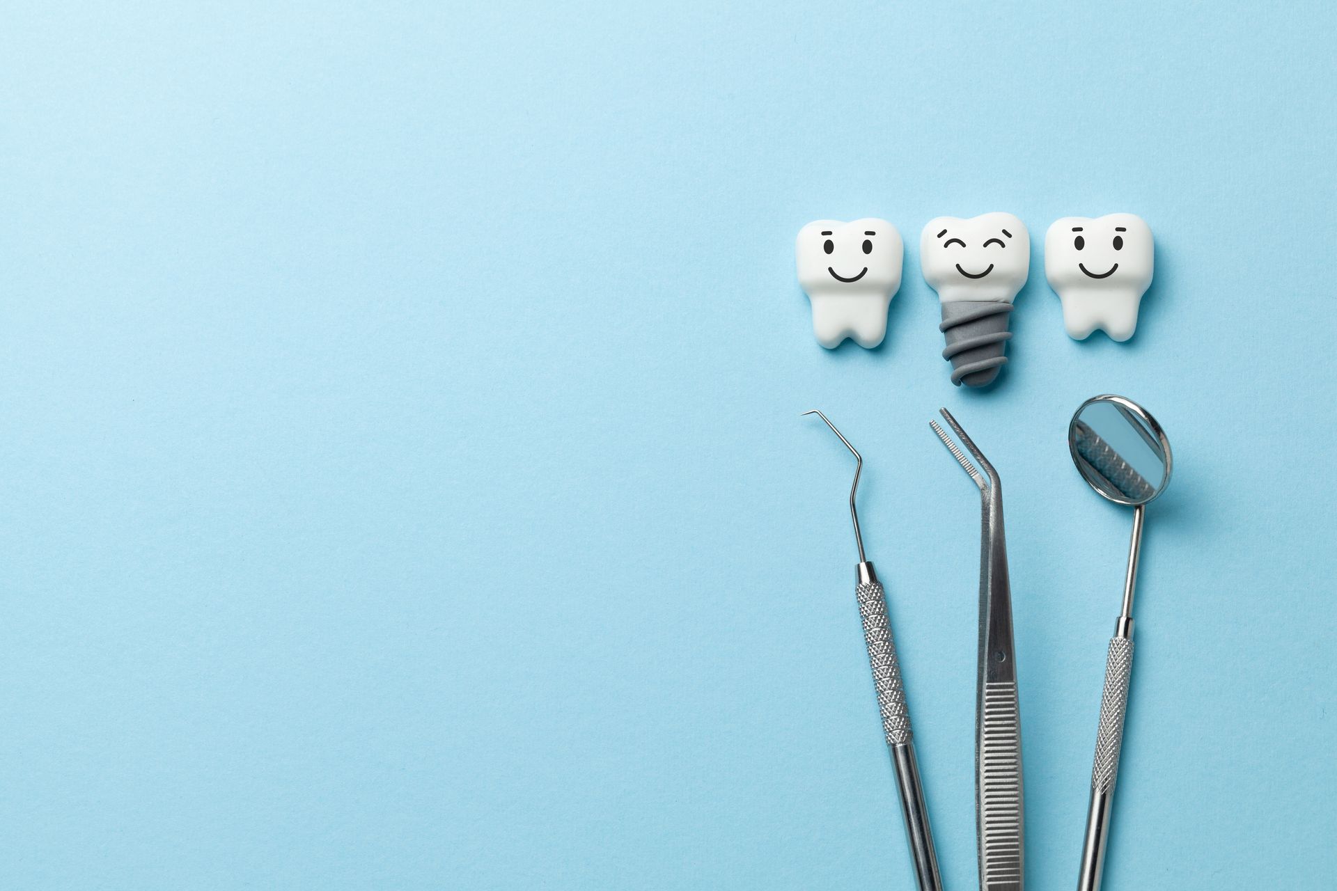 Des outils dentaires à côté de trois modèles de dents avec des visages dessinés.