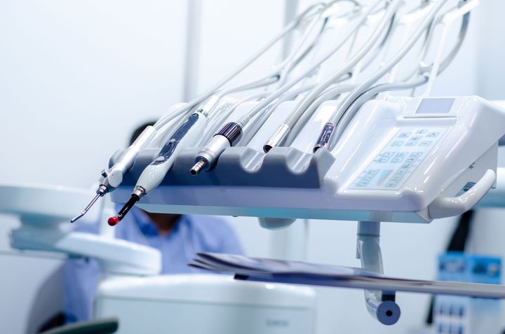 Dans une clinique lumineuse, des instruments dentaires sont disposés sur un plateau, tubes et pièces à main prêts à l'emploi.