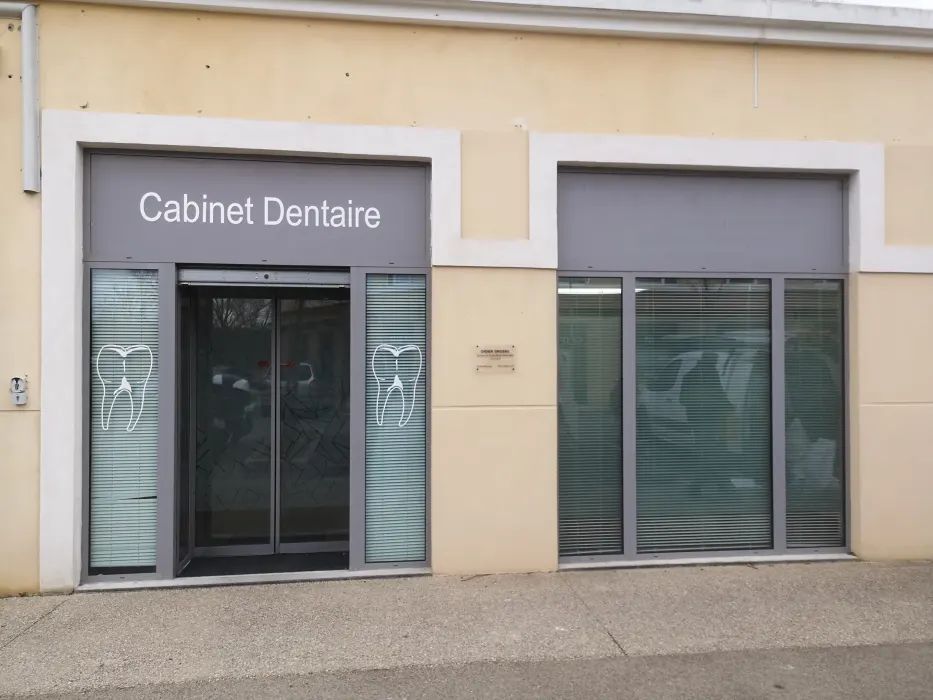 Façade de cabinet dentaire avec portes et fenêtres vitrées, enseigne indiquant Cabinet Dentaire.