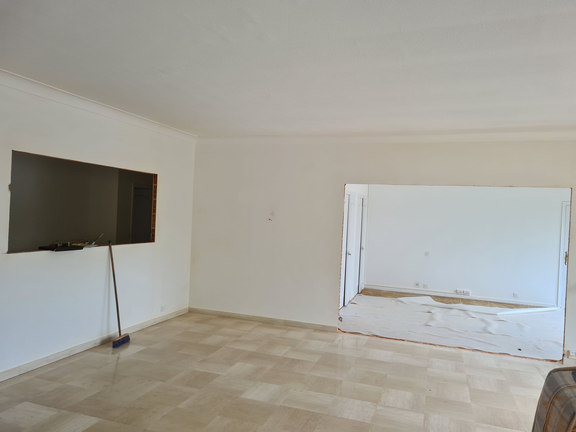 Pièce vide avec une télévision fixée au mur à gauche et une grande ouverture dans le mur du fond.