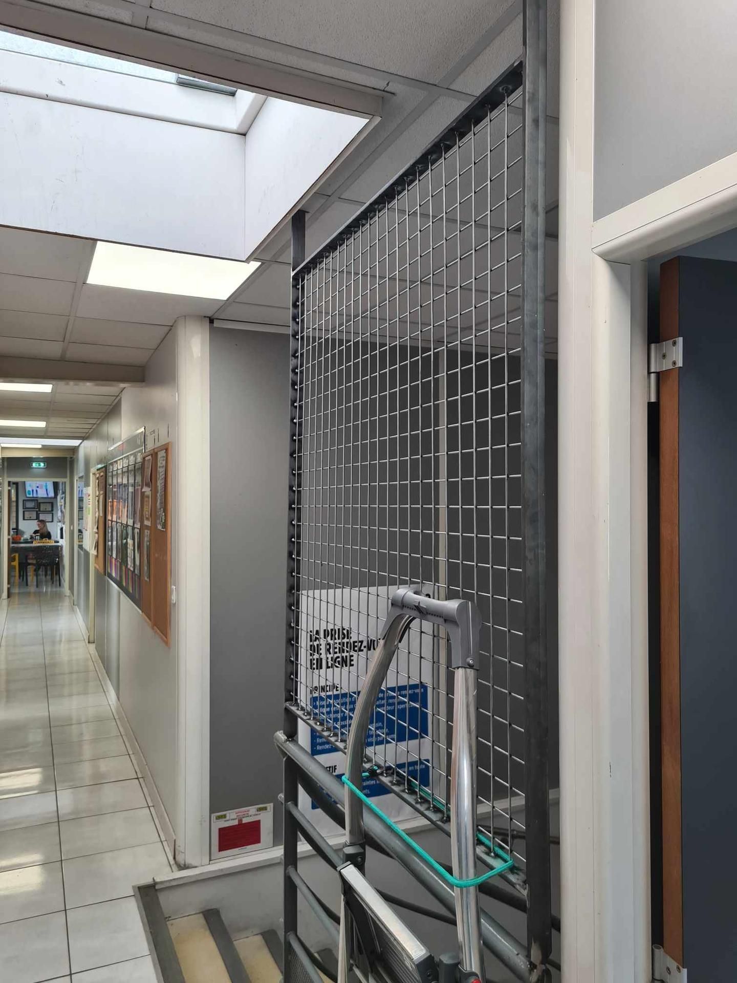 Façade de magasin fermée dans un couloir de centre commercial, avec un chariot plié garé à côté.