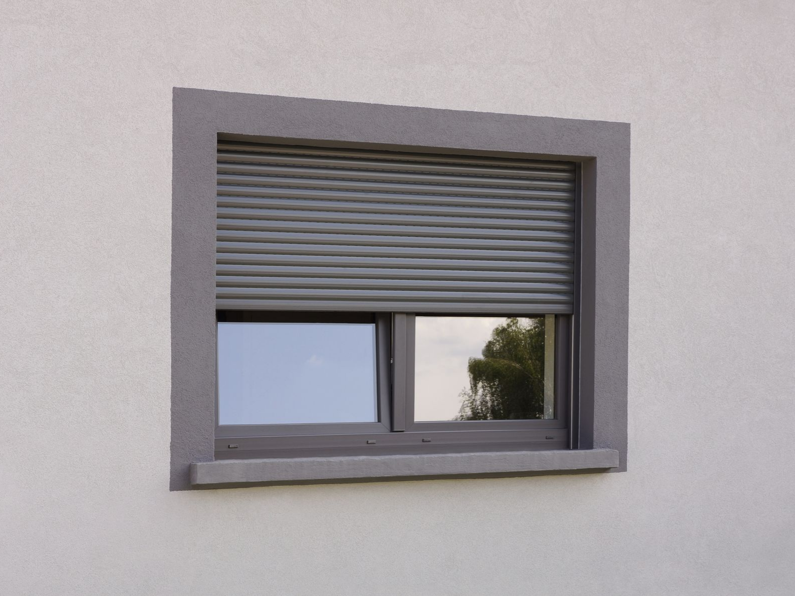 Fenêtre extérieure grise avec un volet partiellement fermé.