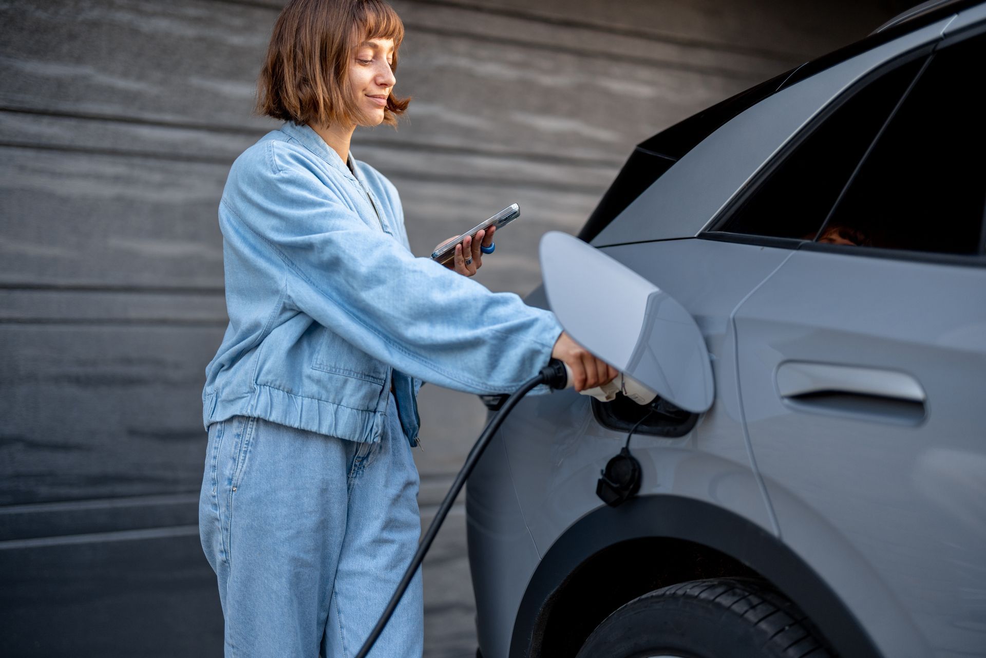 Jeune femme recharge sa voiture devant sa maison