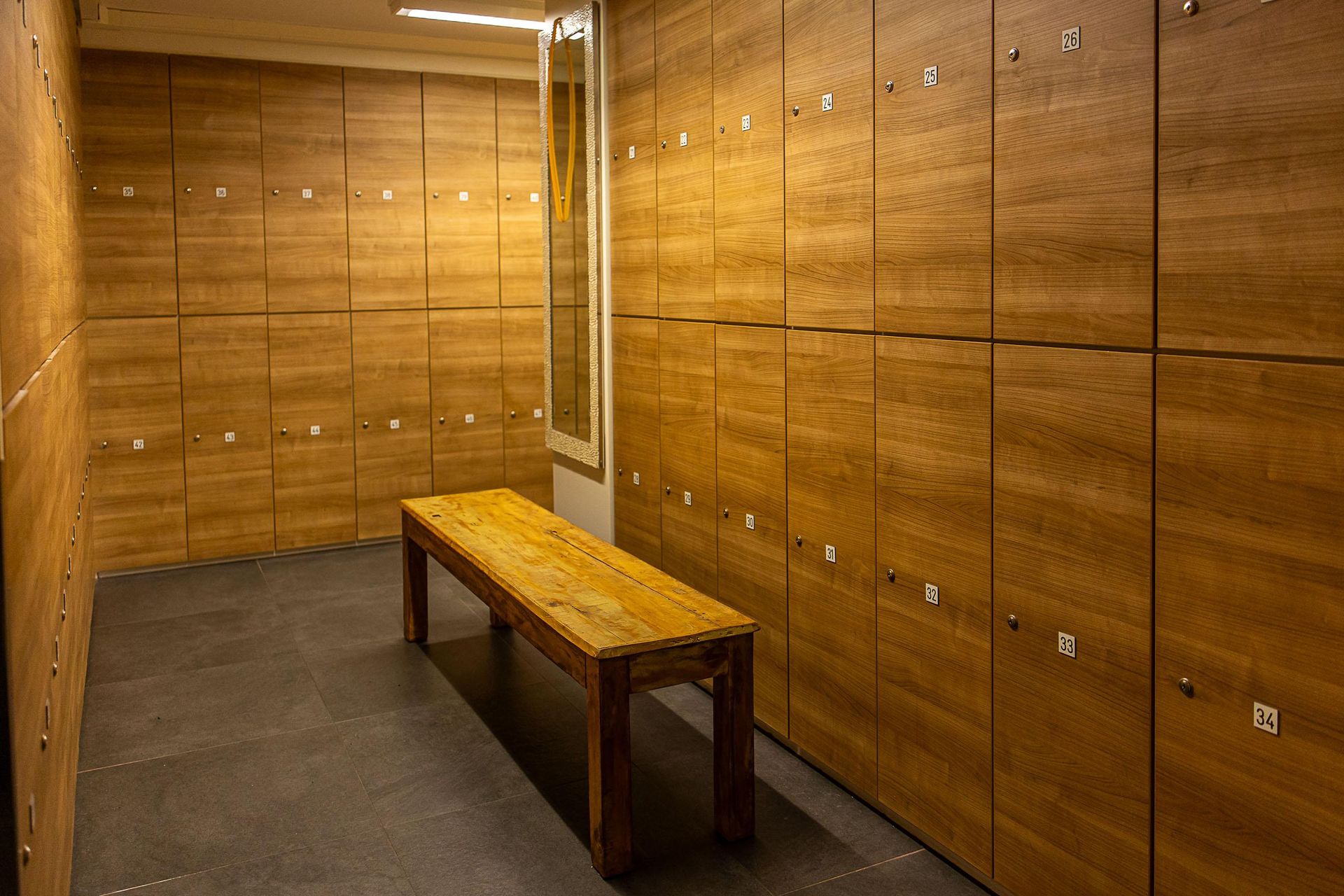 Ein Umkleideraum mit vielen Holzspinden und einer Bank.