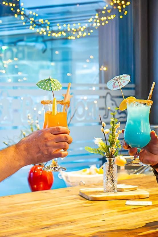 Ein Mann und eine Frau stoßen auf einem Holztisch mit Cocktails an.