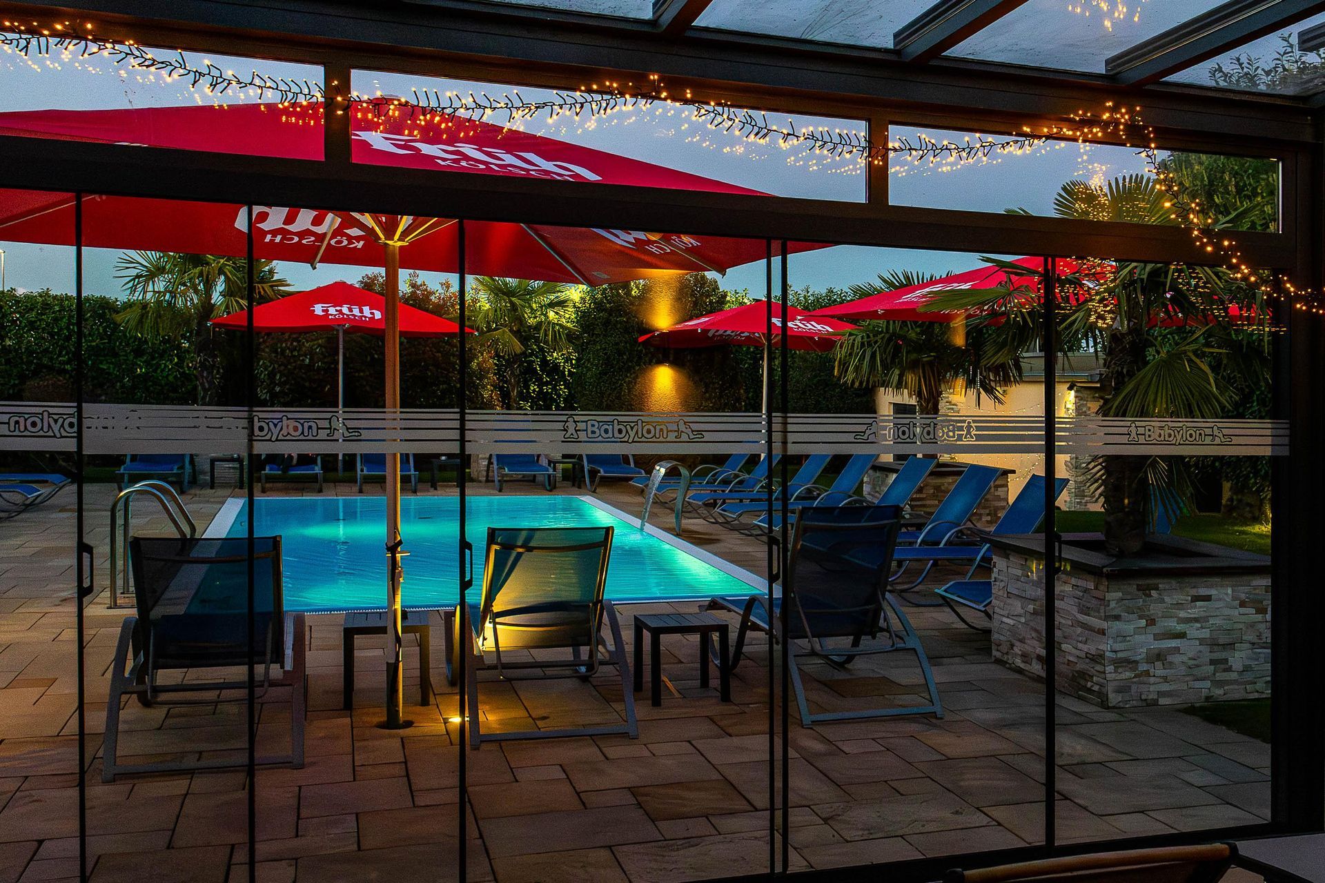Ein Swimmingpool mit roten Sonnenschirmen und Stühlen