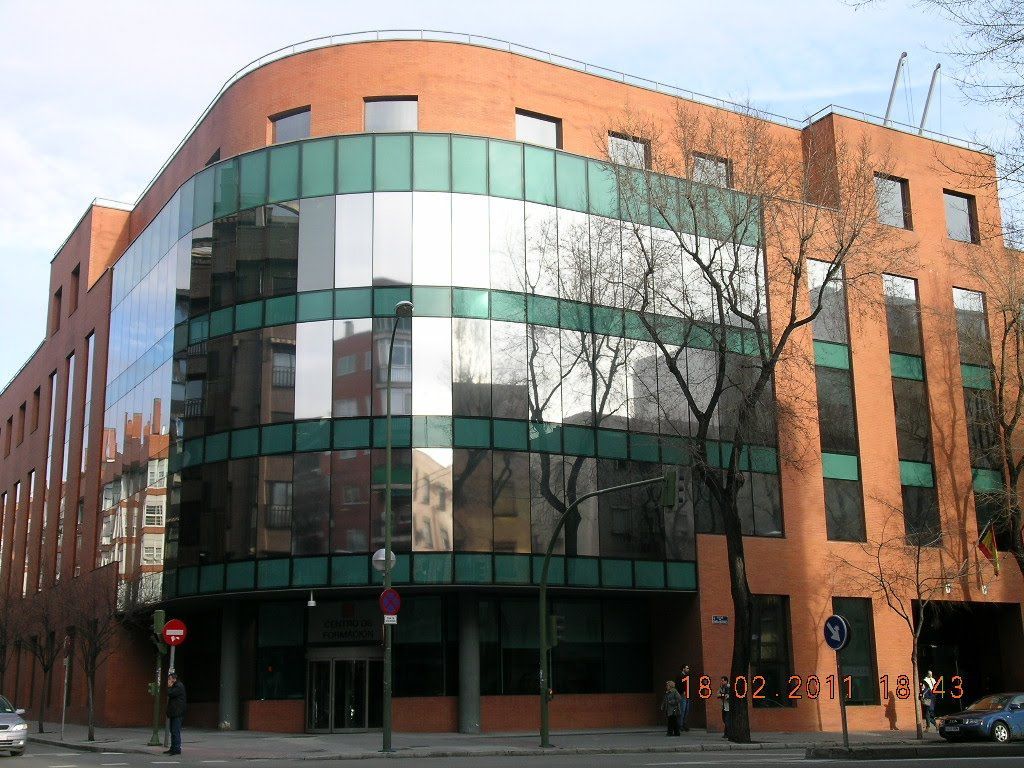Rascacielos de cristal que refleja el cielo azul y las nubes.