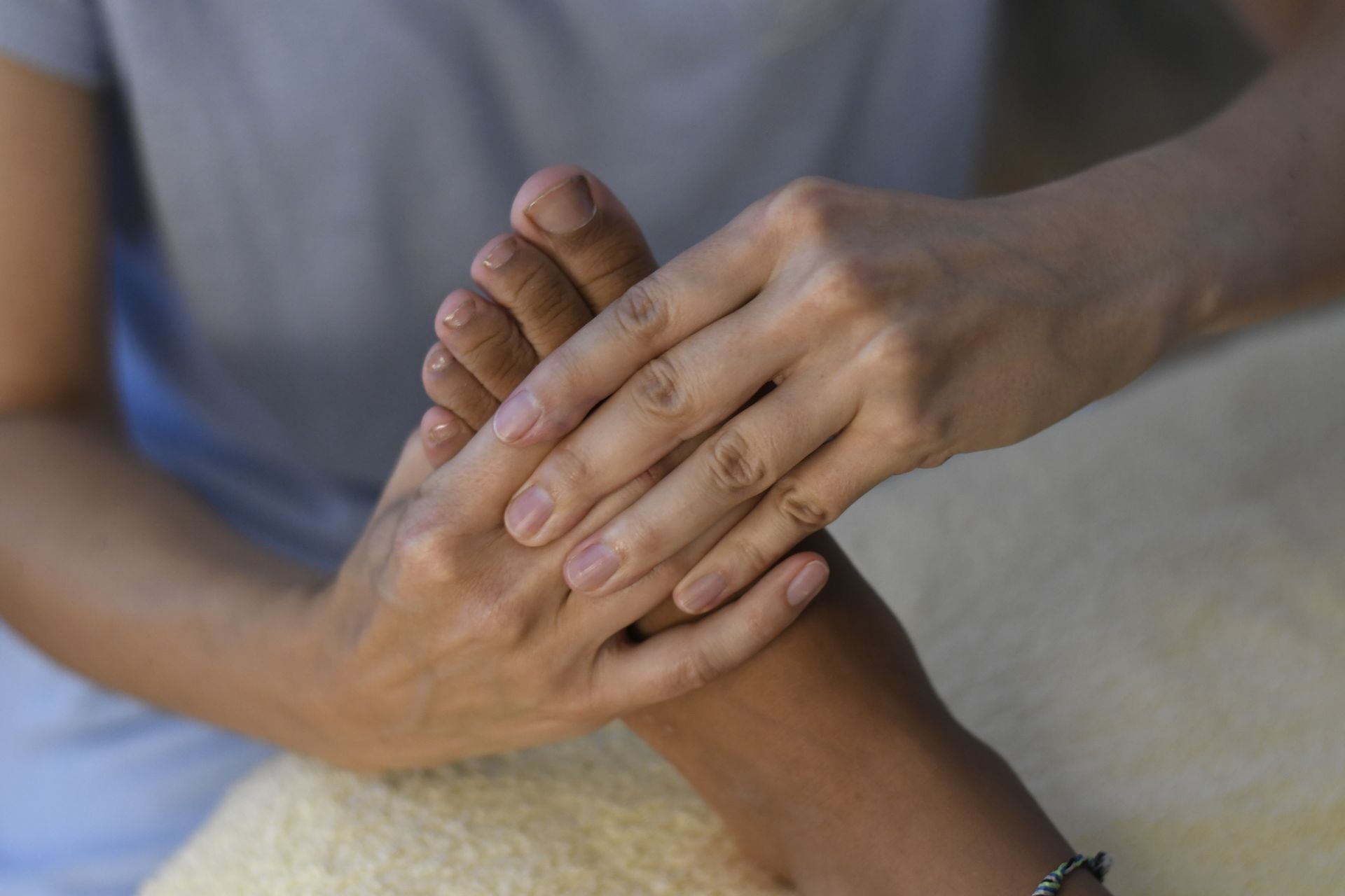Une personne en vêtements blancs médite avec les mains en position mudra, anneau visible, à l'intérieur.