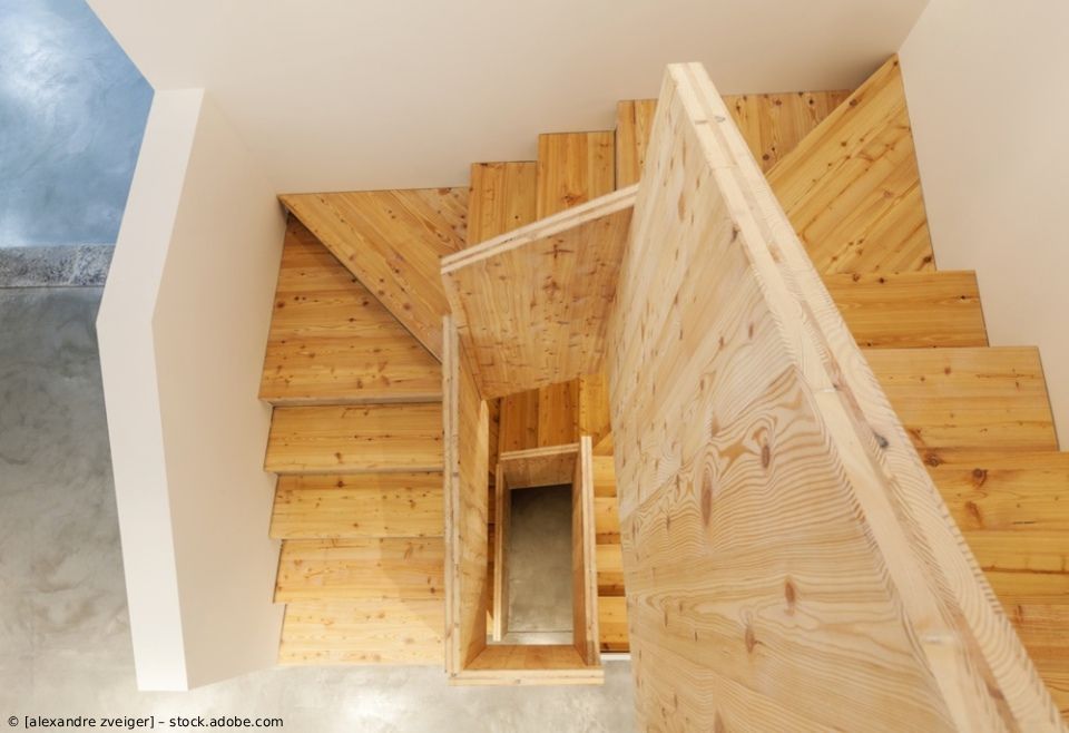 Hölzerne Wendeltreppe mit hellen Wänden und einem zentralen offenen Schacht, von oben betrachtet