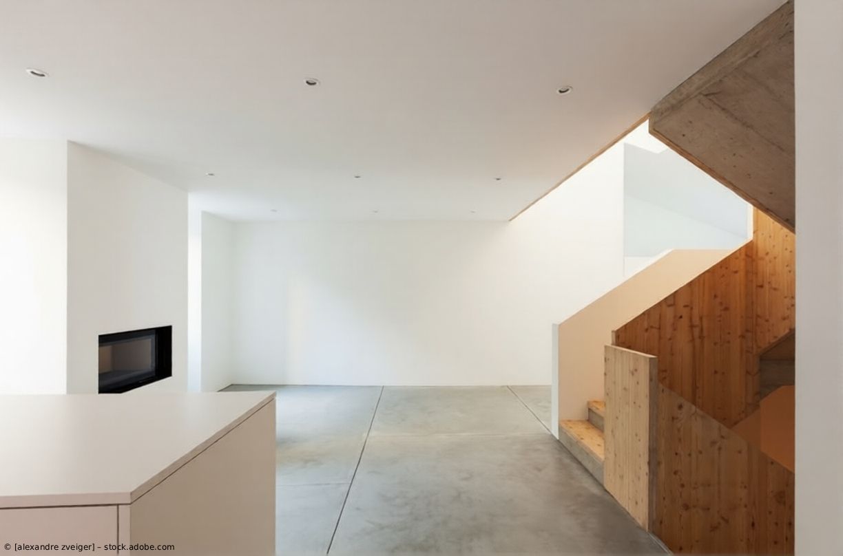 Minimalistisches, weißes Interieur mit Betonboden, Kamin links und Holztreppe rechts.