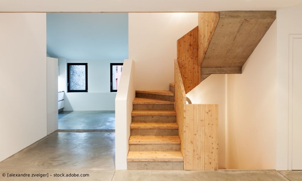 Minimalistisches Interieur mit Treppe zum Dachboden und zwei gerahmten Fenstern in einem hellen Raum