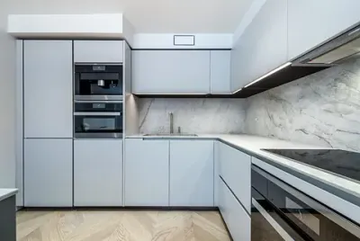 Una cocina con gabinetes blancos, electrodomésticos de acero inoxidable, un fregadero y un horno de estufa.