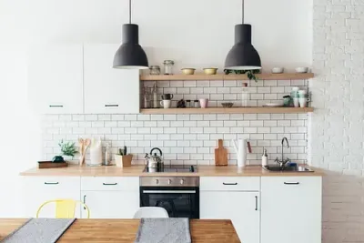 Una cocina con gabinetes blancos, una estufa, un fregadero y una mesa.