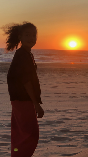 Enfant sur la plage face au couché de soleil