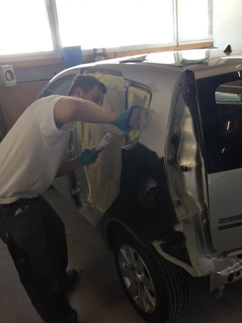 Ein Mann im weißen Hemd arbeitet an einem Auto