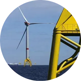 Aerogenerador marino con estructura de soporte amarilla en un mar azul.