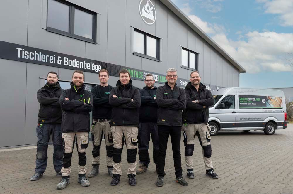 Eine Gruppe Männer posiert vor einem Gebäude für ein Foto.
