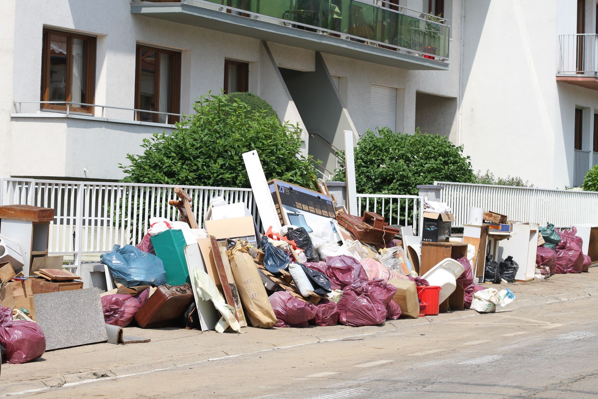 Tas d'objets ménagers jetés, de sacs-poubelle et de débris sur le trottoir.