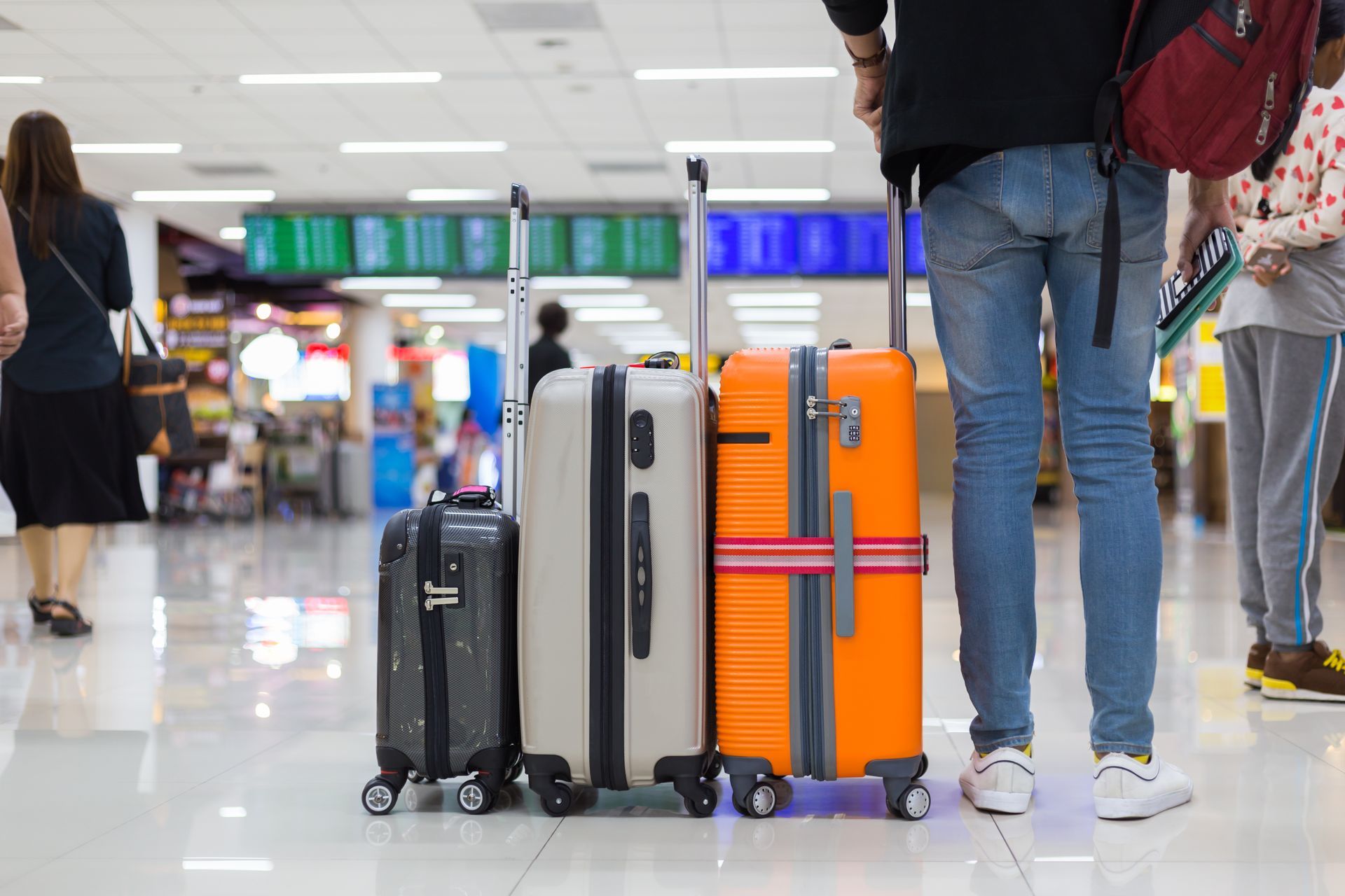 Un homme à l'aéroport vu de dos attend avec 3 valises
